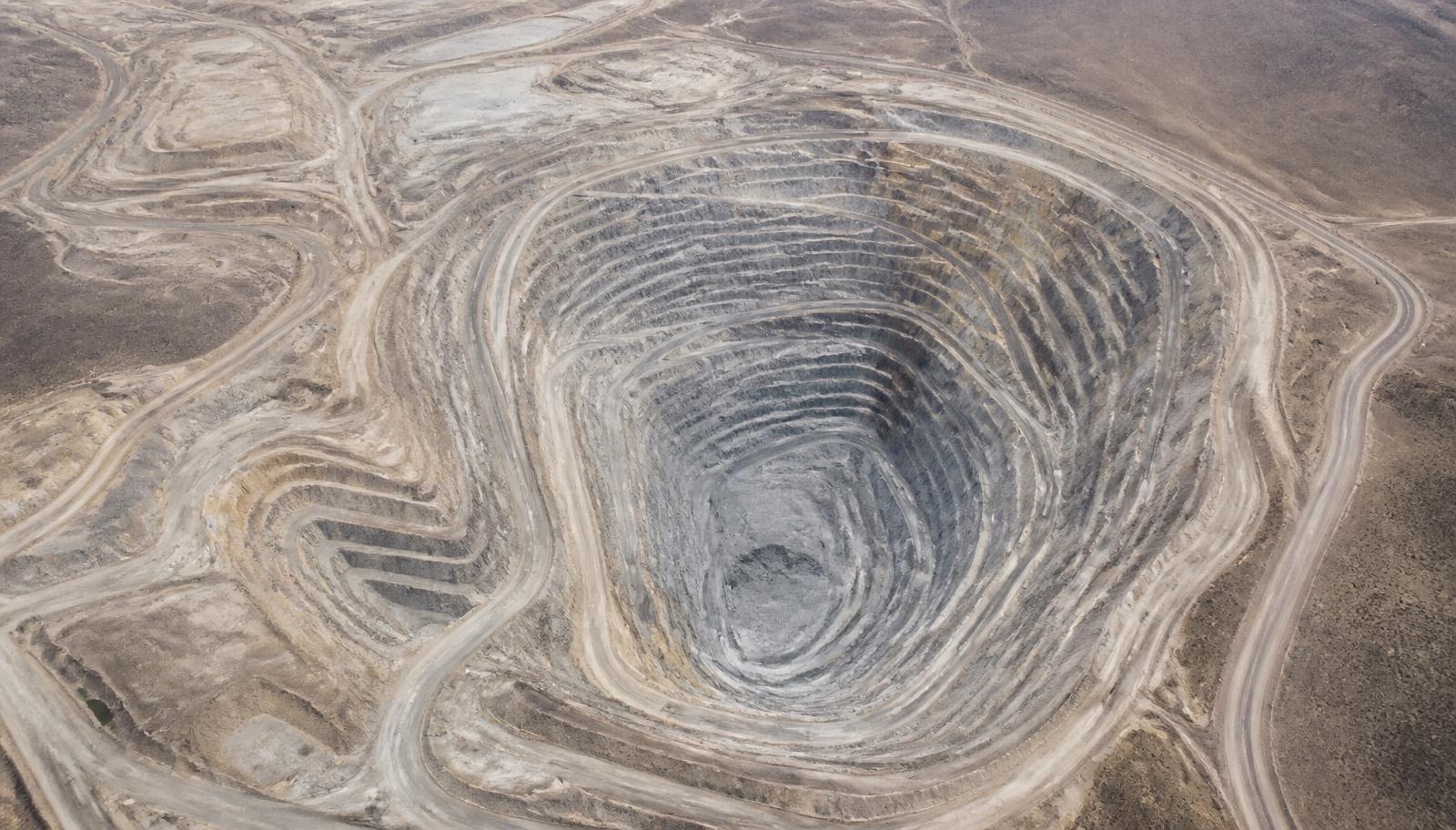Aerial view of a large open-pit mine crossing arid terrain far beyond network coverage